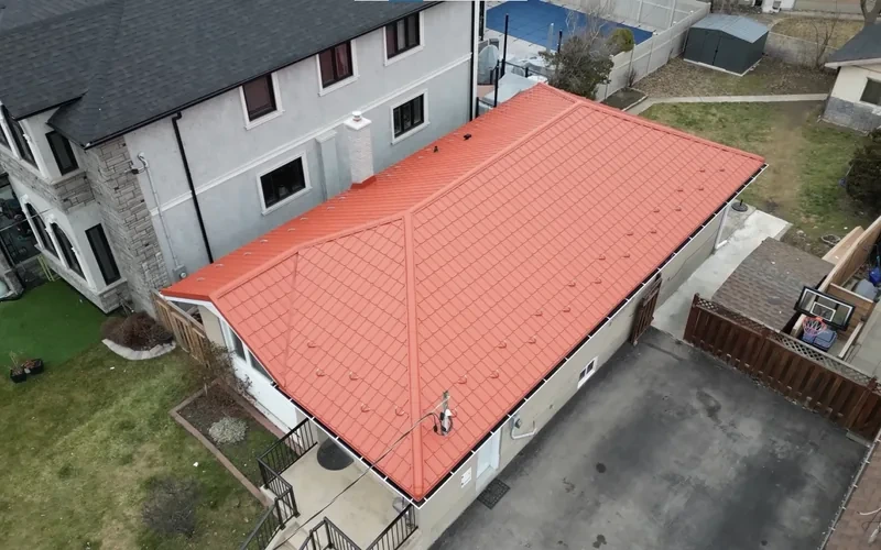 Aerial view of a Spring, TX home with a new red metal roof installed by a local roofing team